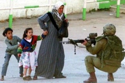 Israeli soldier points gun at woman and children