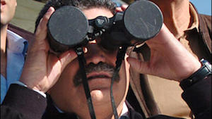Israeli Defence Minister Amir Peretz observing military manoeuvres through binoculars with the lens caps still on