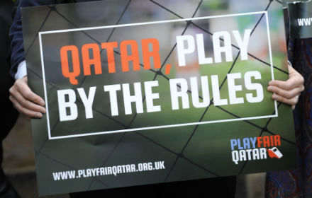 Person holding placard saying Qatar Play Fair